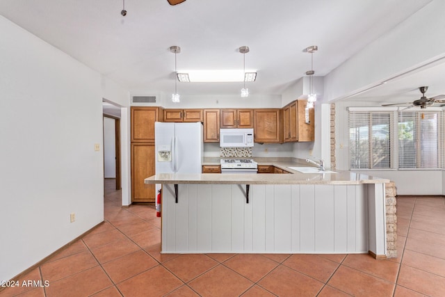 kitchen with decorative light fixtures, sink, a kitchen breakfast bar, kitchen peninsula, and white appliances