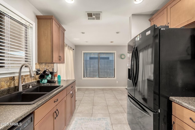 kitchen featuring sink, black fridge, backsplash, plenty of natural light, and light tile patterned floors