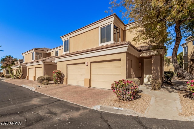 7887 N 16th St Unit 224, Phoenix, AZ 85020 - view of property with stucco siding, a garage, a tiled roof, and decorative driveway