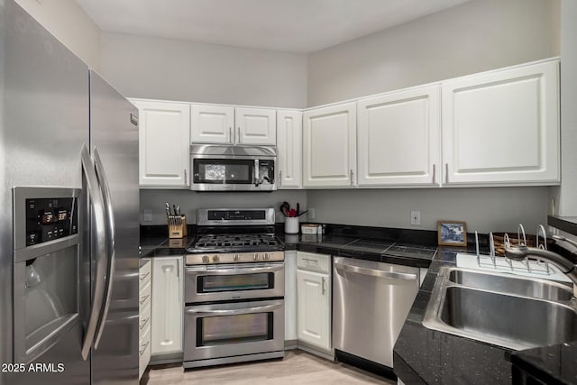 7887 N 16th St Unit 224, Phoenix, AZ 85020 - kitchen with appliances with stainless steel finishes, white cabinets, light wood-style flooring, and tile countertops