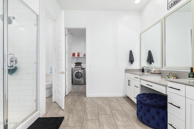 bathroom with washer / clothes dryer, vanity, an enclosed shower, and toilet