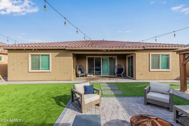 back of house with a lawn, a patio, and an outdoor fire pit