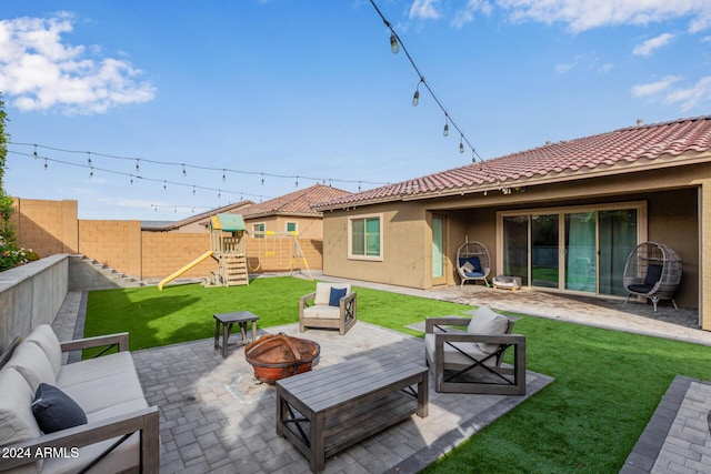 view of patio with a playground and an outdoor living space with a fire pit