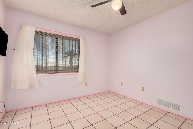 spare room featuring ceiling fan, light tile patterned floors, and a textured ceiling