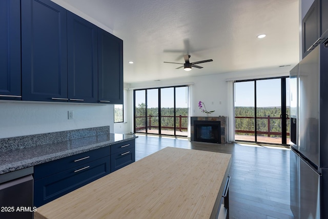 2943 E Lookout Ln, Overgaard, AZ 85933 - kitchen with stainless steel fridge, blue cabinets, a ceiling fan, wood finished floors, and recessed lighting