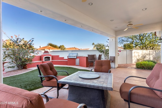 view of patio / terrace with ceiling fan, a grill, exterior kitchen, and exterior fireplace