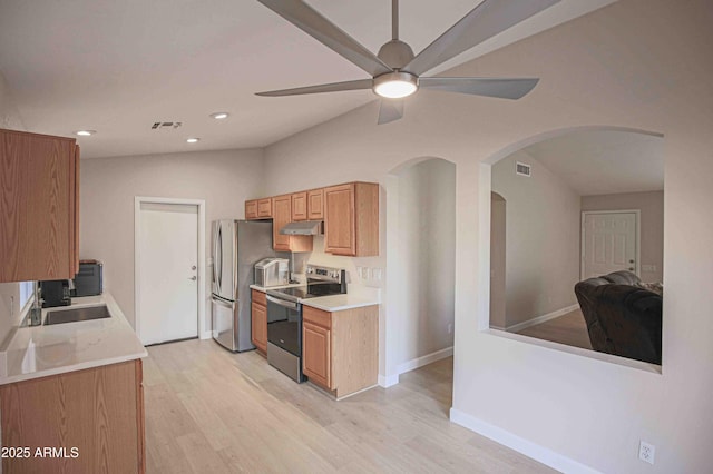 kitchen featuring appliances with stainless steel finishes, light hardwood / wood-style floors, sink, vaulted ceiling, and ceiling fan