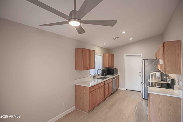 kitchen featuring stainless steel dishwasher, vaulted ceiling, ceiling fan, sink, and light wood-type flooring