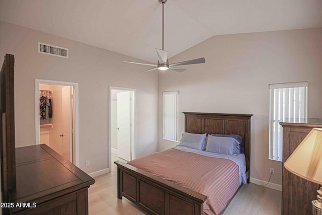 bedroom featuring ceiling fan, connected bathroom, light hardwood / wood-style flooring, and lofted ceiling