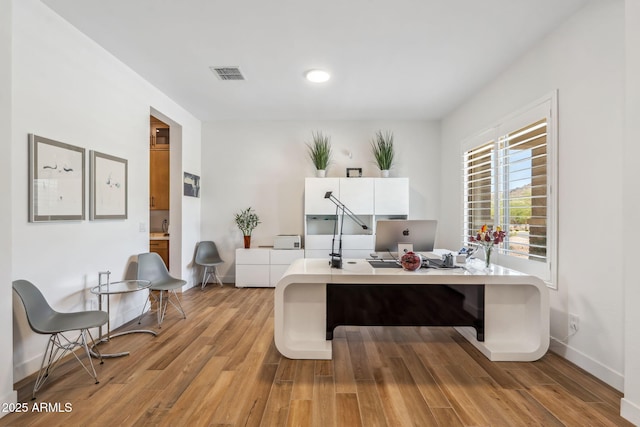 office area with baseboards, visible vents, and light wood-type flooring
