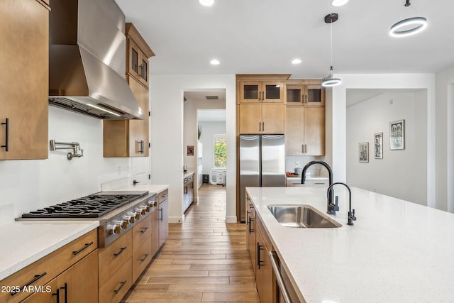 kitchen with stainless steel gas cooktop, light wood-style floors, recessed lighting, wall chimney exhaust hood, and a sink