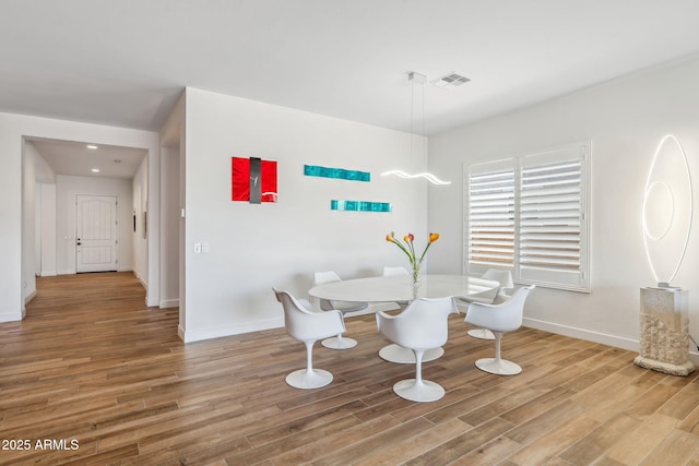 dining room featuring baseboards, visible vents, and wood finished floors