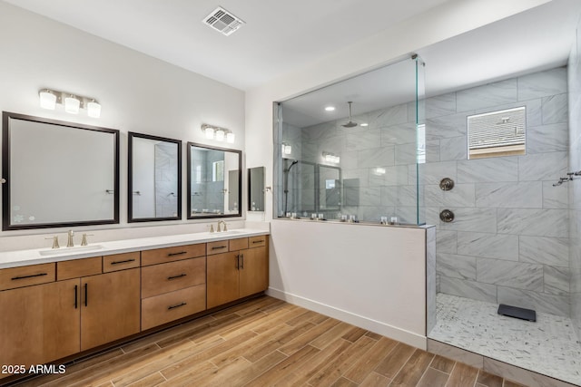 bathroom with a walk in shower, visible vents, a sink, and wood finished floors