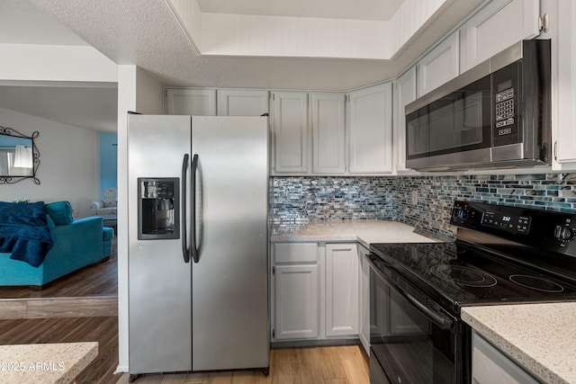 kitchen featuring white cabinets, appliances with stainless steel finishes, light hardwood / wood-style floors, and backsplash