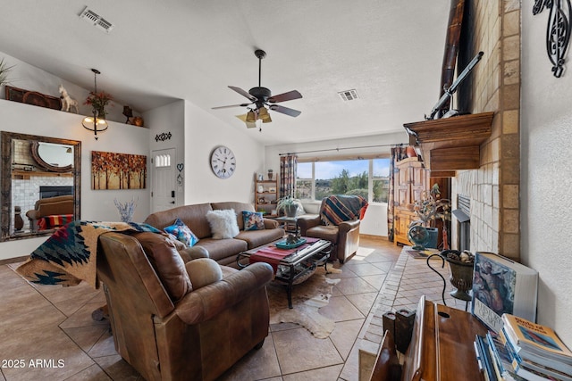 tiled living room featuring ceiling fan, vaulted ceiling, and a tile fireplace