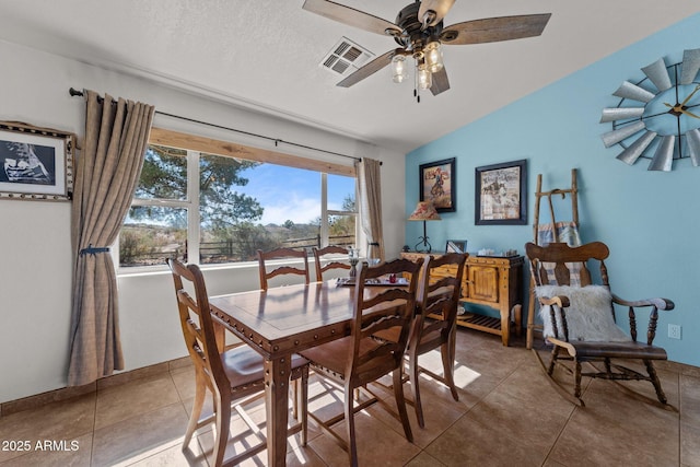 tiled dining space with vaulted ceiling, a textured ceiling, and ceiling fan