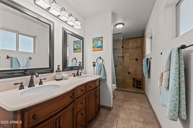 bathroom with vanity, toilet, tile patterned flooring, and a tile shower