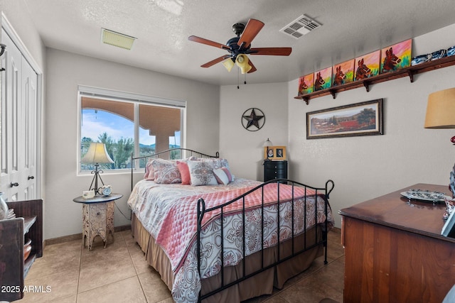 tiled bedroom featuring ceiling fan, a closet, and a textured ceiling