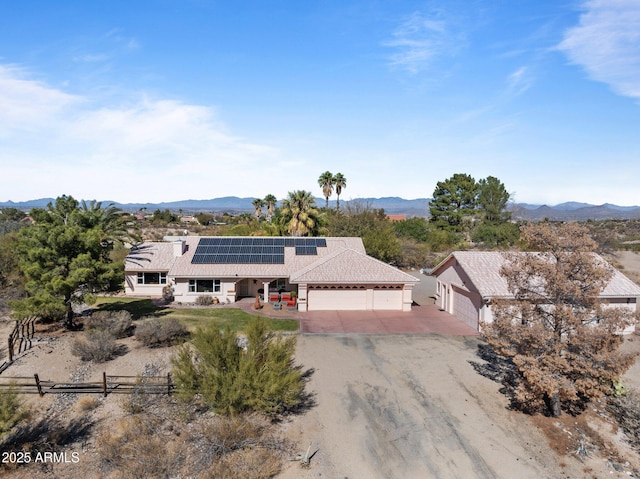 view of front of property with a mountain view, a garage, and solar panels