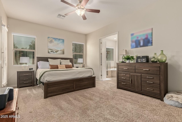 bedroom featuring light carpet, ensuite bathroom, and ceiling fan