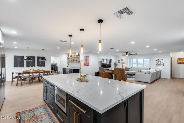 9005 W Villa Chula St, Peoria, AZ 85383 - kitchen featuring appliances with stainless steel finishes, light wood-style floors, recessed lighting, a kitchen island, and dark cabinets