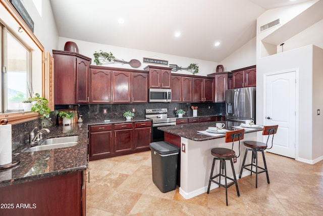 3597 W Mineral Butte Dr, San Tan Valley, AZ 85144 - kitchen with appliances with stainless steel finishes, backsplash, a kitchen breakfast bar, vaulted ceiling, and dark stone countertops