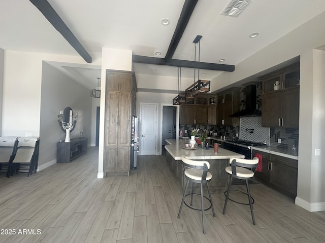 29476 N Wolfe Trl, Florence, AZ 85132 - kitchen with wall chimney range hood, beam ceiling, light countertops, light wood-style floors, and backsplash