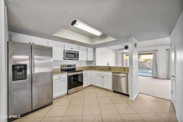 kitchen featuring light tile patterned floors, white cabinetry, appliances with stainless steel finishes, and a tray ceiling