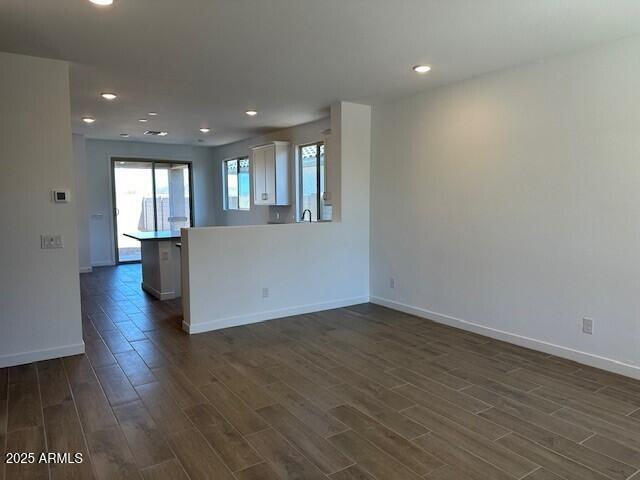 empty room featuring recessed lighting, baseboards, and dark wood-style floors