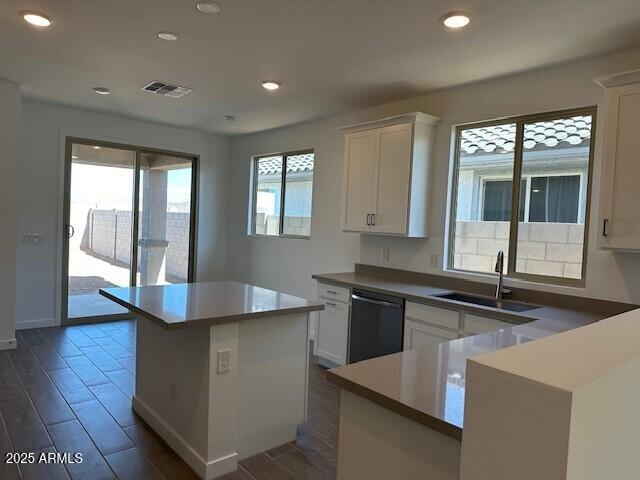 kitchen featuring dishwasher, white cabinetry, wood finish floors, and a sink