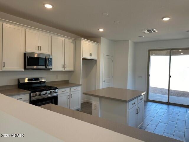 kitchen with appliances with stainless steel finishes, recessed lighting, white cabinets, and visible vents