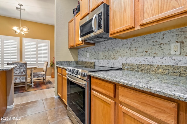 kitchen with backsplash, hanging light fixtures, stainless steel appliances, light stone countertops, and light tile patterned flooring