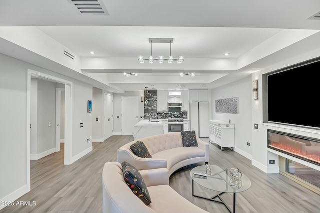 living room featuring visible vents, baseboards, and light wood-style floors