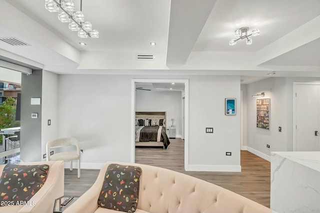 interior space featuring a raised ceiling, wood finished floors, visible vents, and baseboards