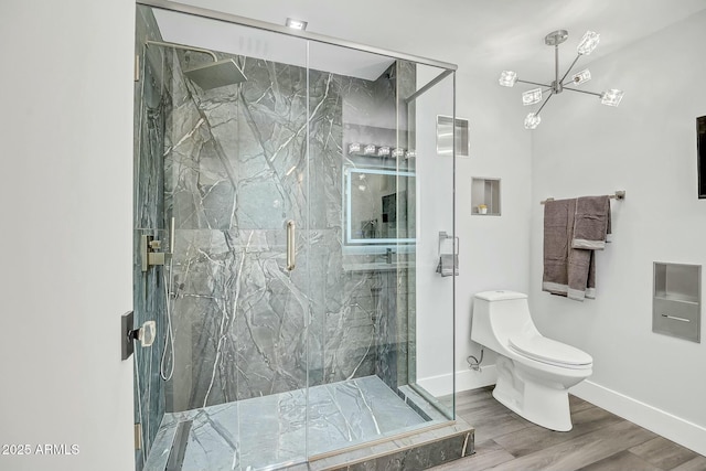 bathroom with a marble finish shower, toilet, baseboards, and wood finished floors