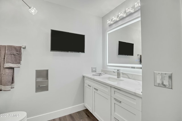 bathroom featuring vanity, toilet, wood finished floors, and baseboards