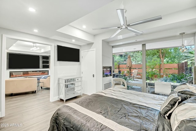 bedroom with a glass covered fireplace, recessed lighting, and wood finished floors