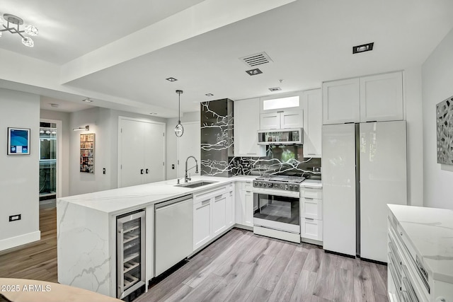 kitchen with visible vents, beverage cooler, a sink, stainless steel appliances, and a peninsula