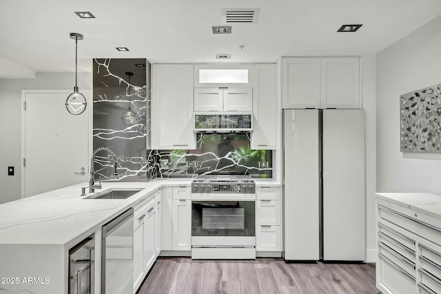 kitchen featuring light stone counters, a sink, white cabinets, appliances with stainless steel finishes, and light wood-type flooring