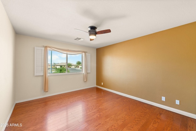 unfurnished room featuring ceiling fan, visible vents, baseboards, and wood finished floors