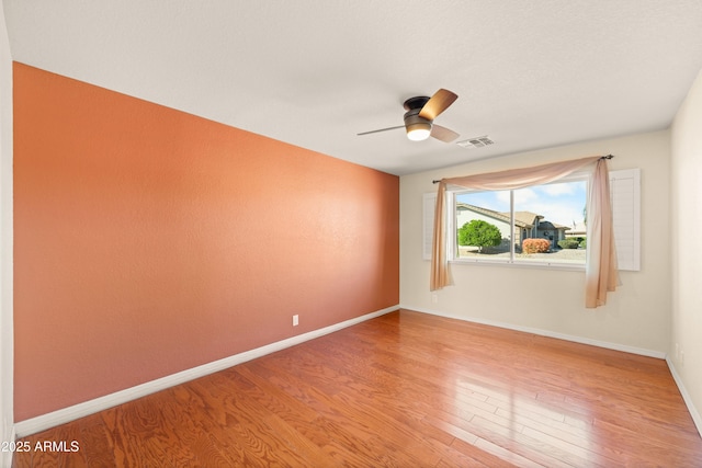 spare room featuring light wood-style flooring, baseboards, visible vents, and ceiling fan