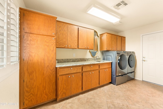 laundry area featuring visible vents, light tile patterned flooring, cabinet space, a sink, and independent washer and dryer