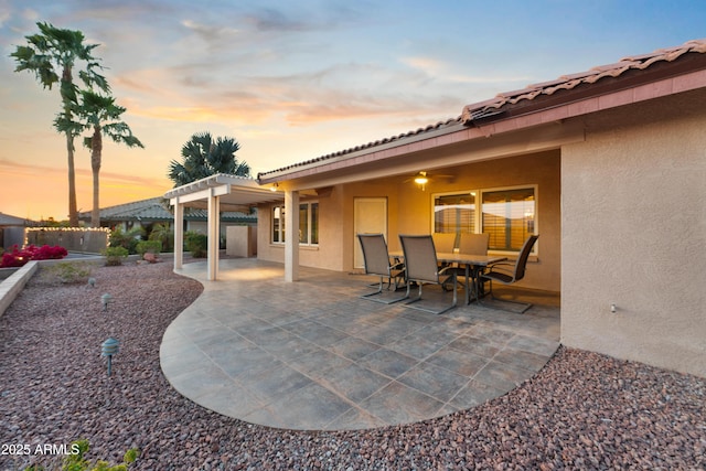 patio terrace at dusk with outdoor dining area and a pergola