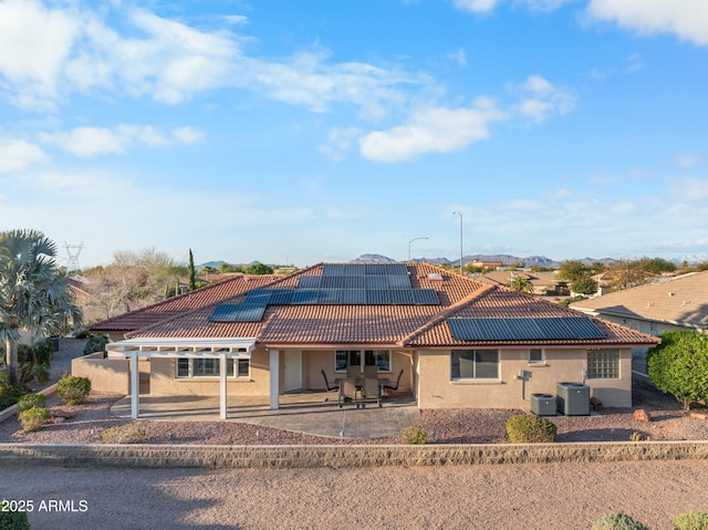 rear view of property featuring a patio area, central air condition unit, stucco siding, and solar panels