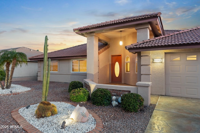 view of front of property with a tiled roof, stucco siding, and an attached garage