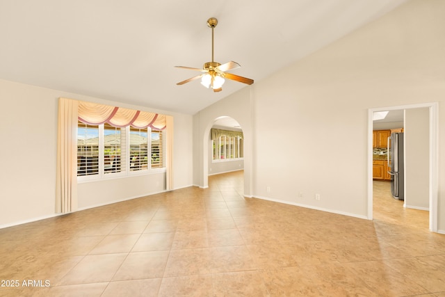 unfurnished room with high vaulted ceiling, arched walkways, light tile patterned flooring, baseboards, and ceiling fan