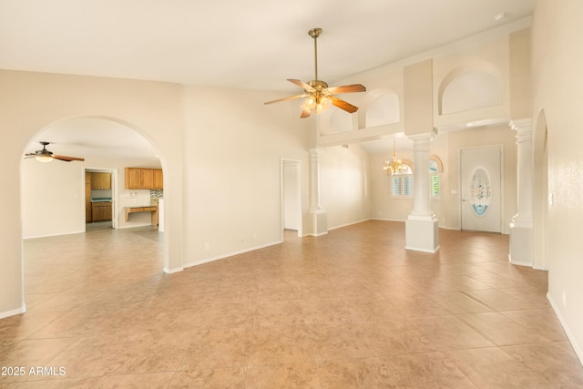 unfurnished living room with arched walkways, ceiling fan, a high ceiling, and ornate columns