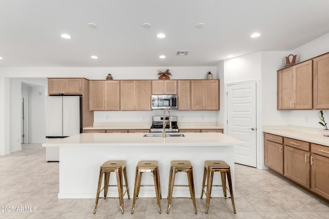 10223 W Piccadilly Rd, Avondale, AZ 85392 - kitchen with stainless steel appliances, recessed lighting, a breakfast bar, a kitchen island with sink, and light countertops