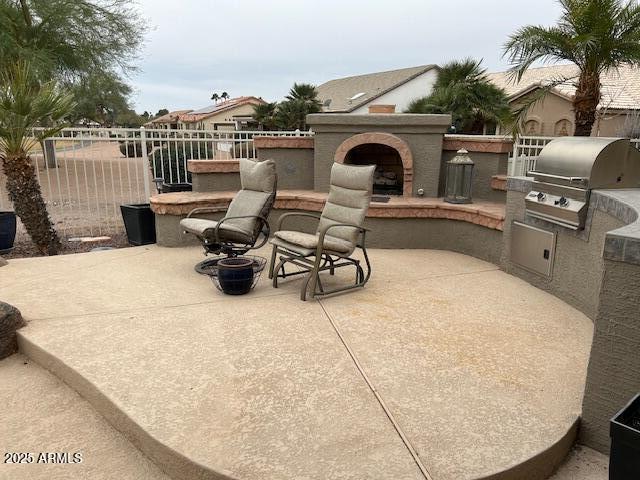 view of patio featuring a grill, fence, an outdoor brick fireplace, and area for grilling