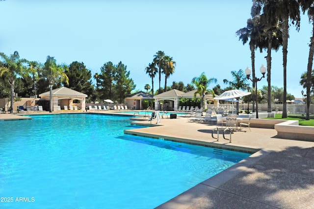 community pool with a patio area and fence